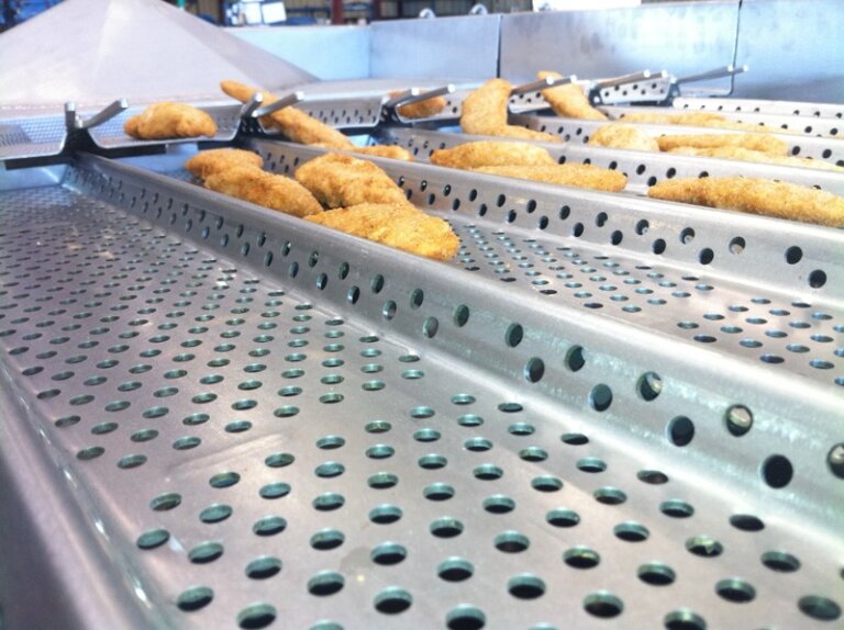 Chicken nuggets traveling down a PFI Laning Vibratory Conveyor.